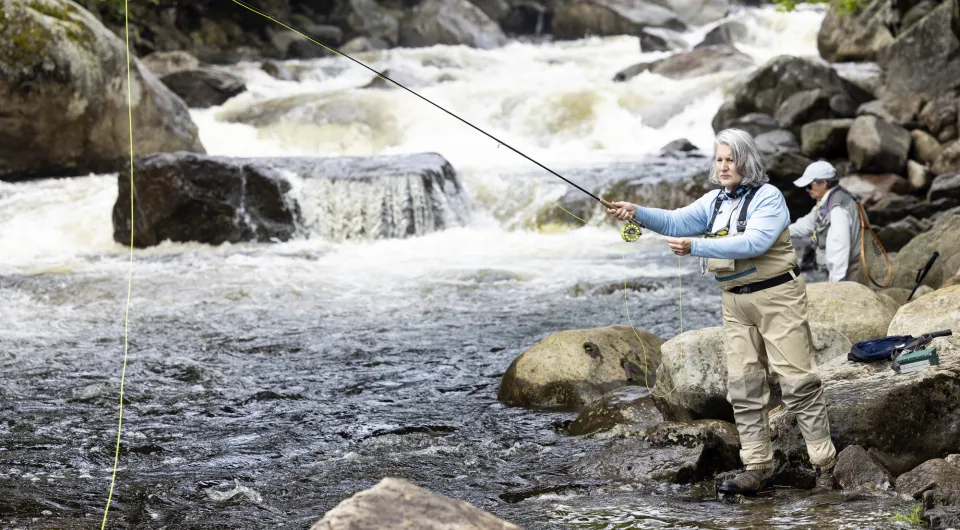 Two women fish in a fast flowing river