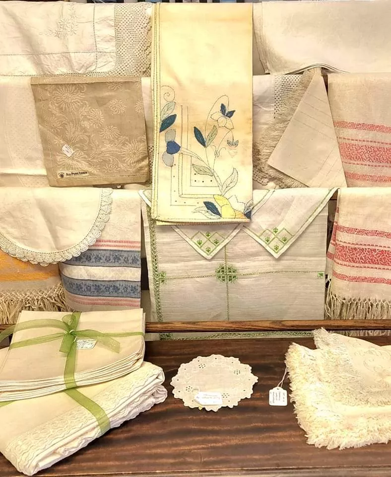 An array of antique textiles, including doilies, pillowcases, and tablecloths.