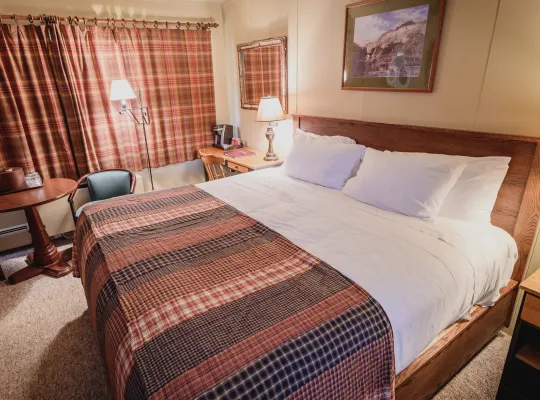 An Adirondack-themed resort hotel room, featuring king-size bed and rustic furnishings.