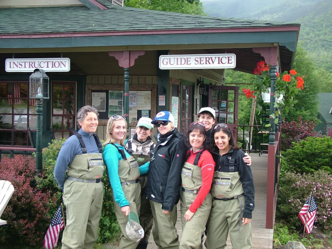 A group of women posing in their waders in front of a local fly shop