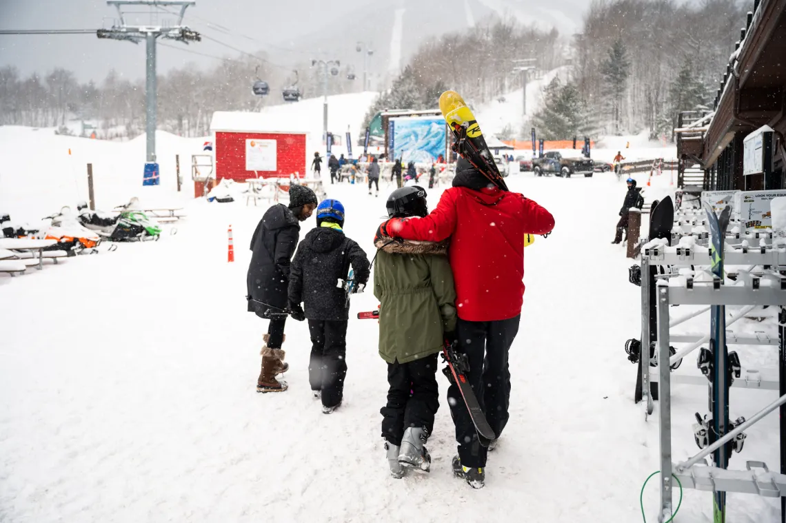 A family walks towards the gondola from the ski lodge