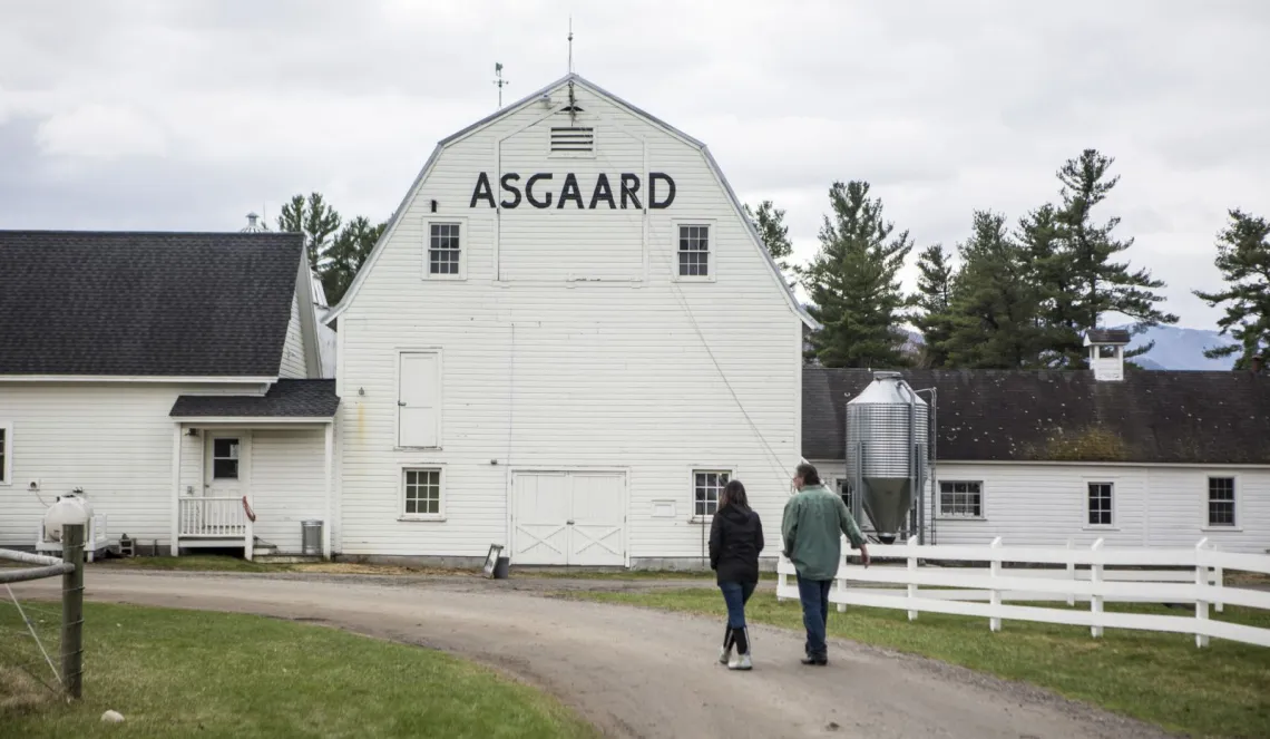 A man and a woman walk down a dirt driveway at Asgaard Farm in Au Sable Forks, New York.