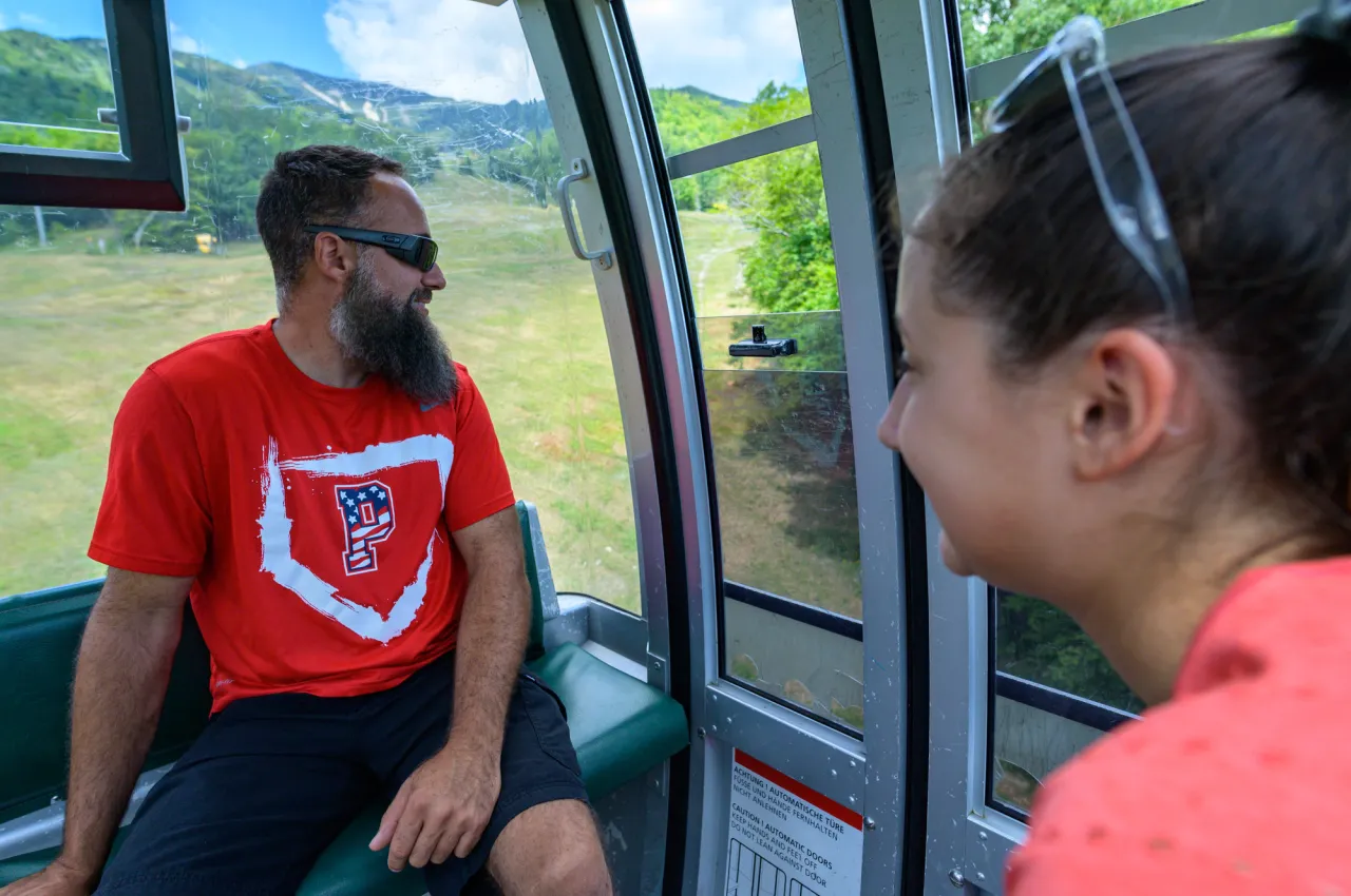 A father and daughter ride up a gondola