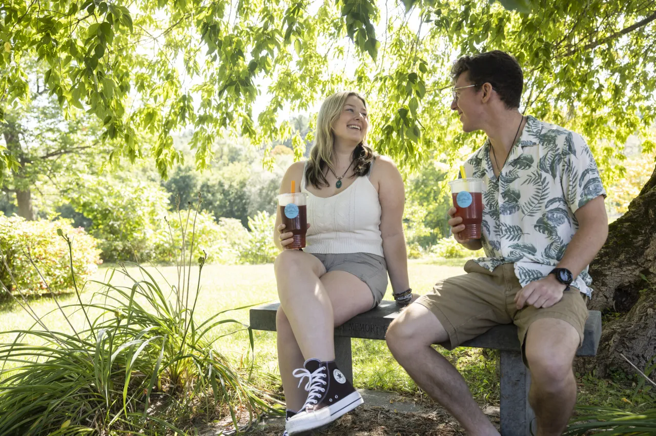 A couple sits in a park with drinks.