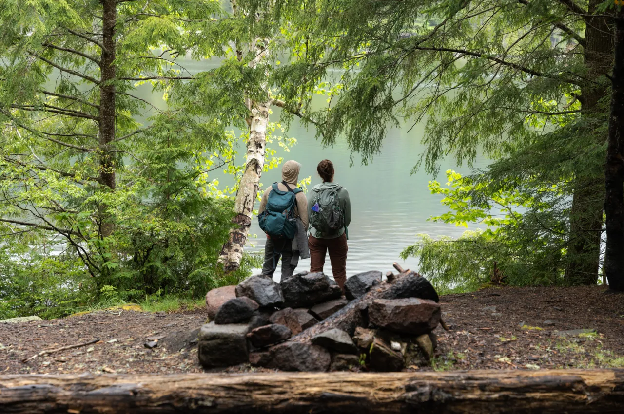 Two people stand in front of an opening on a pond