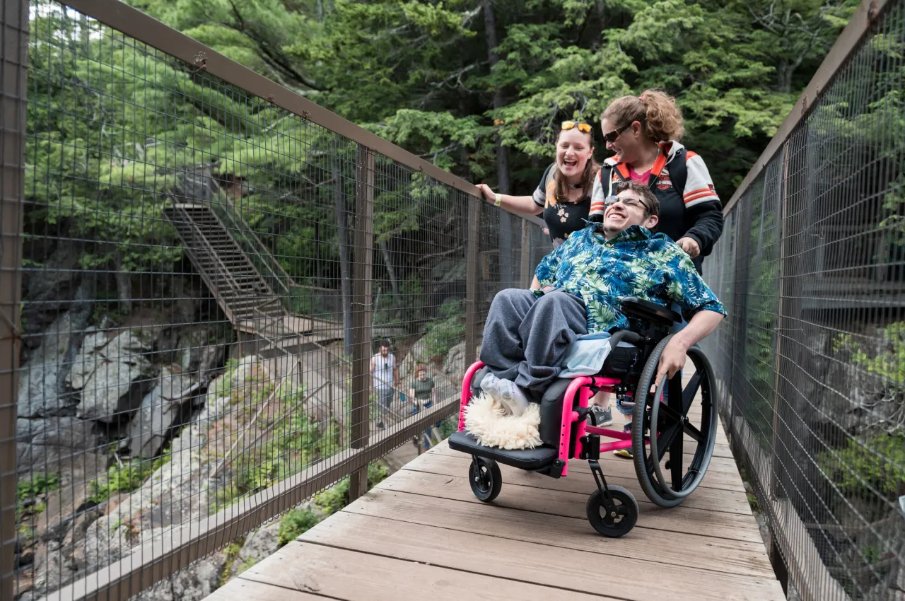 a Group of people laugh on the bridge crossing the Ausable River