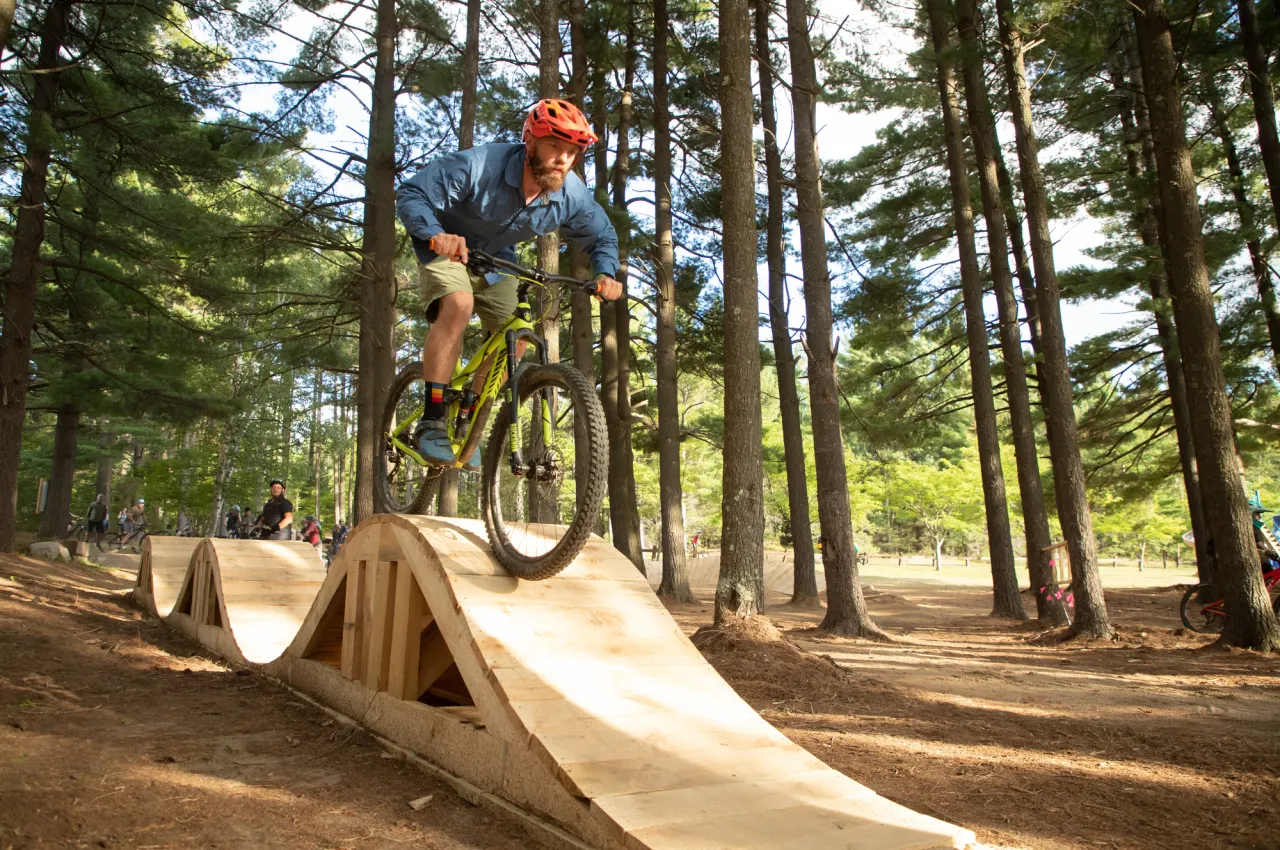 A mountain biker rides on a wavy boardwalk bridge