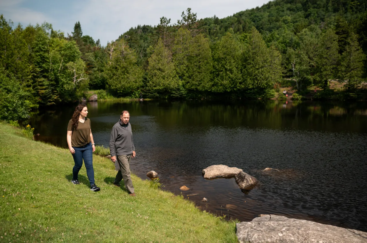 Two people walk past a pond.