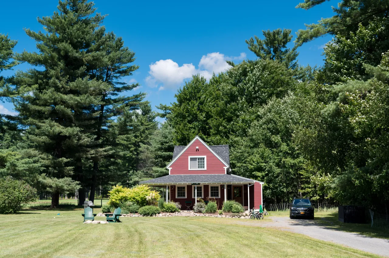 A quant red house sits in the middle of large green trees