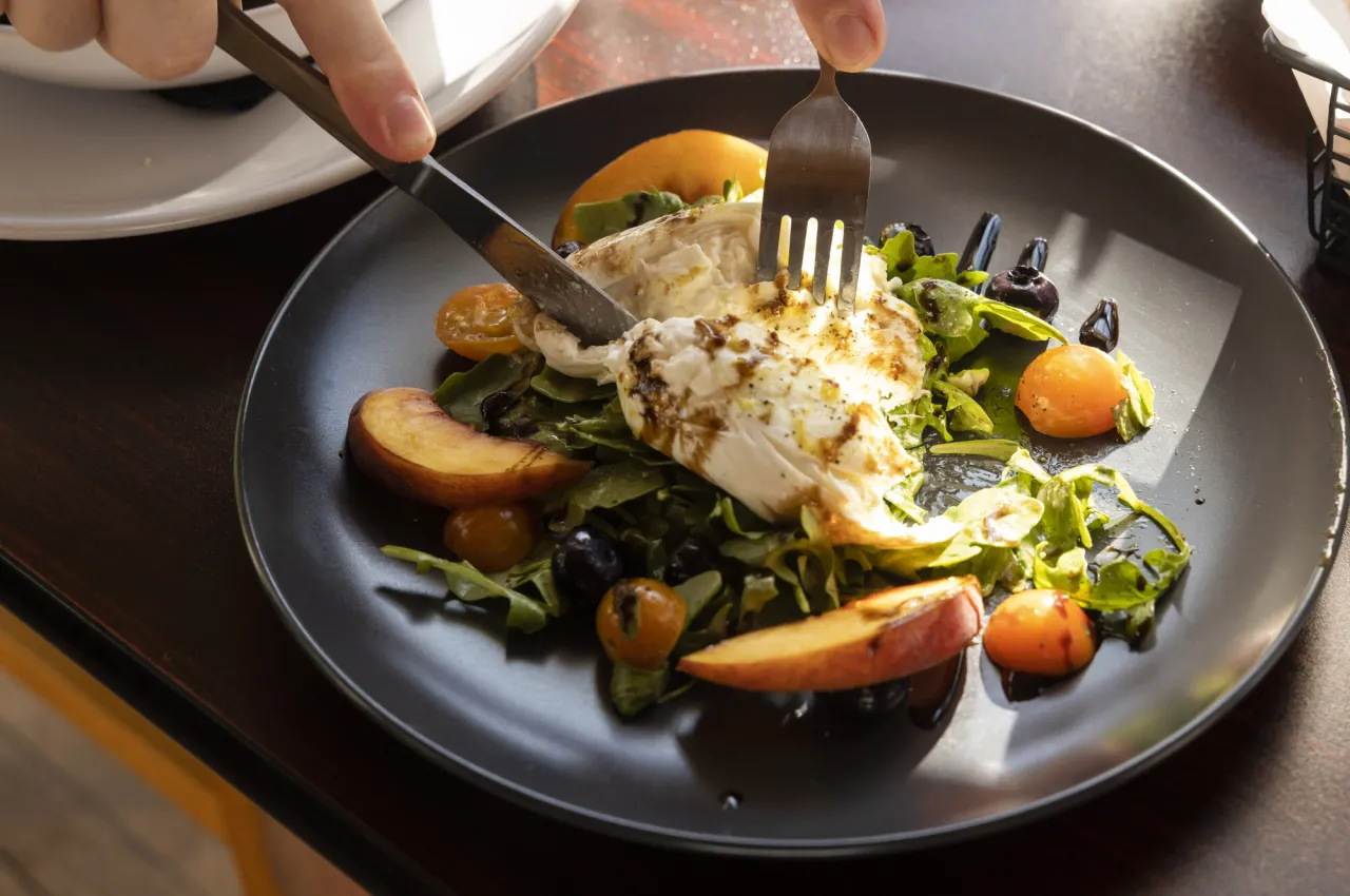 a fork and knife dig into a grilled chicken salad