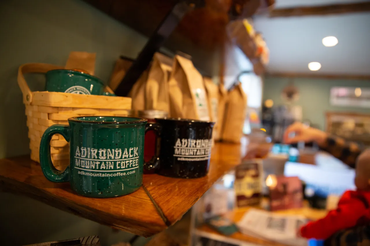 two coffee cups on a shelf with other coffee items