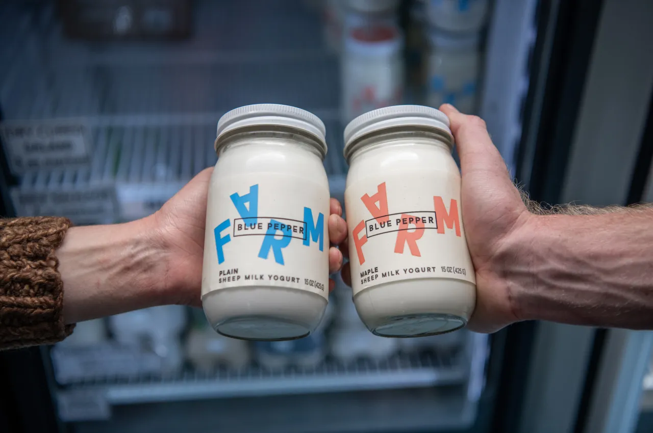 hands hold up glass jars of cream.