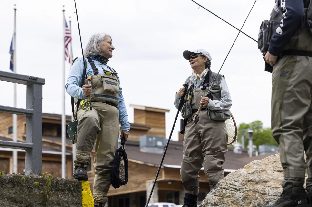 A few people in waders prepare to fly fish
