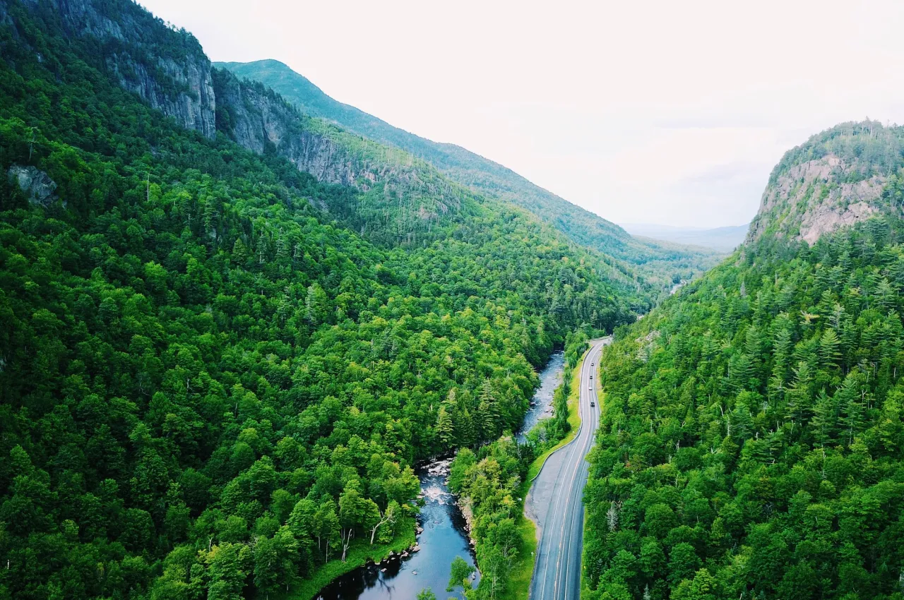 A road runs alongside a winding river in between two rocky cliffs