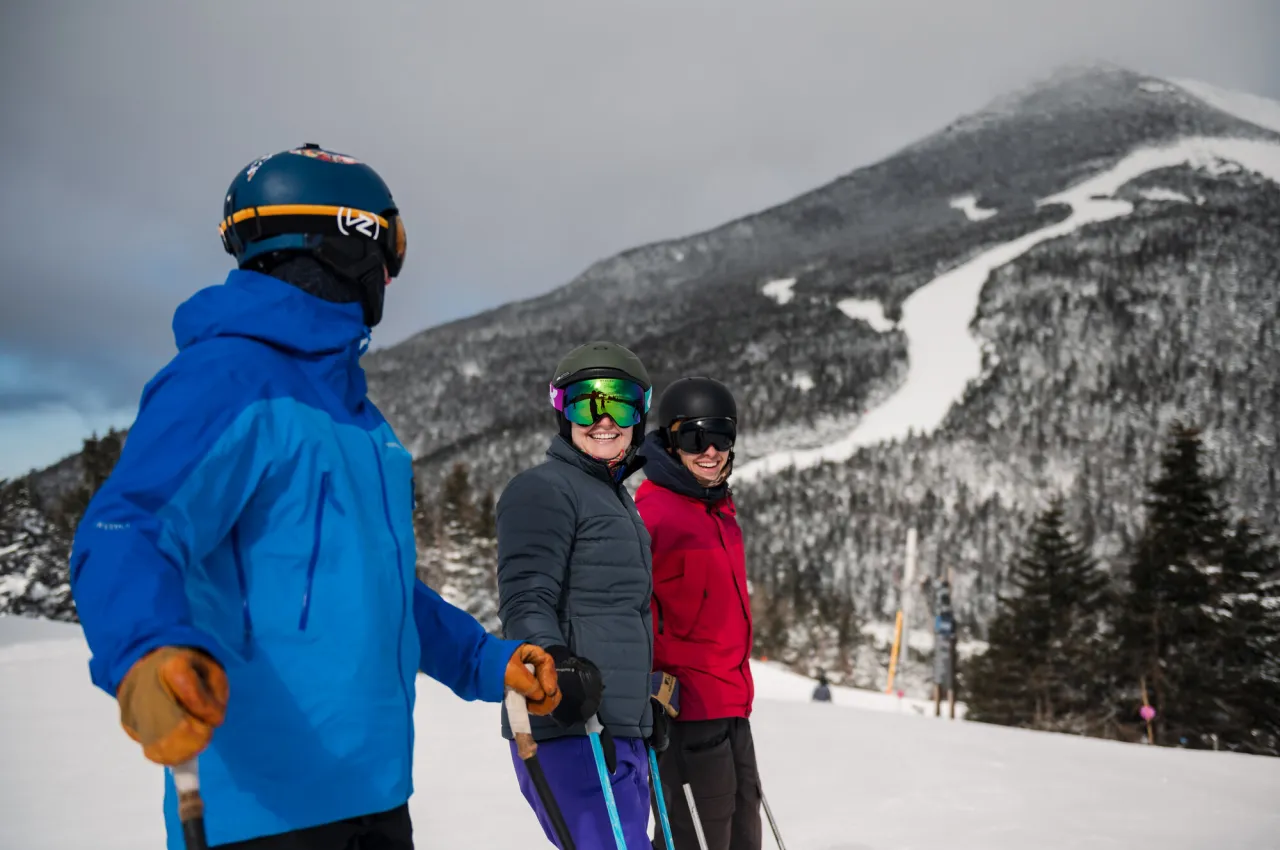 Three skiers laugh and talk on a mountain. 
