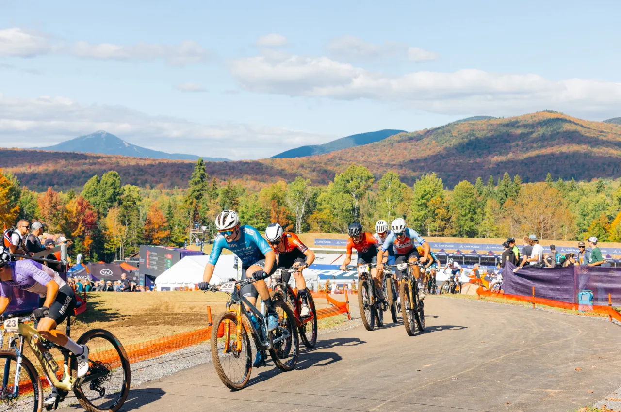 A group of cyclists race on a dirt track.