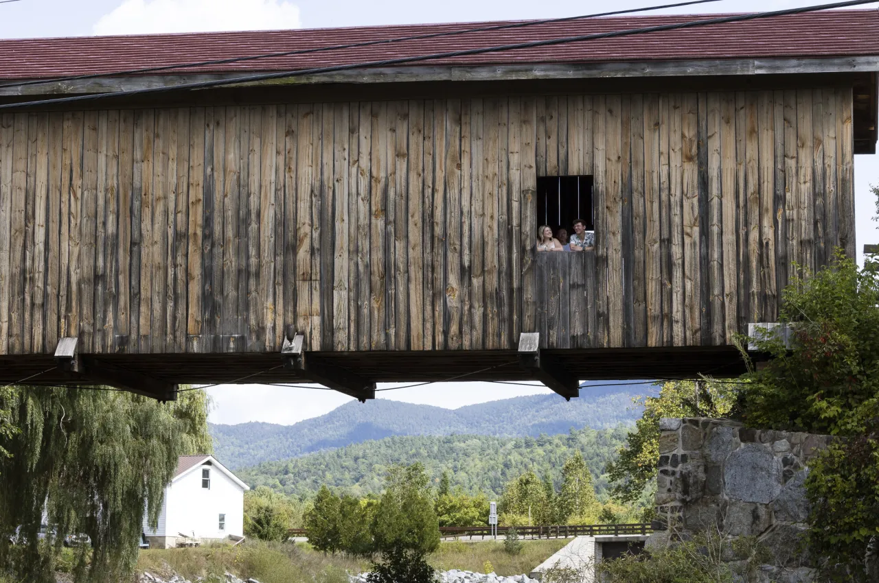 two people walk on a wooden bridge.