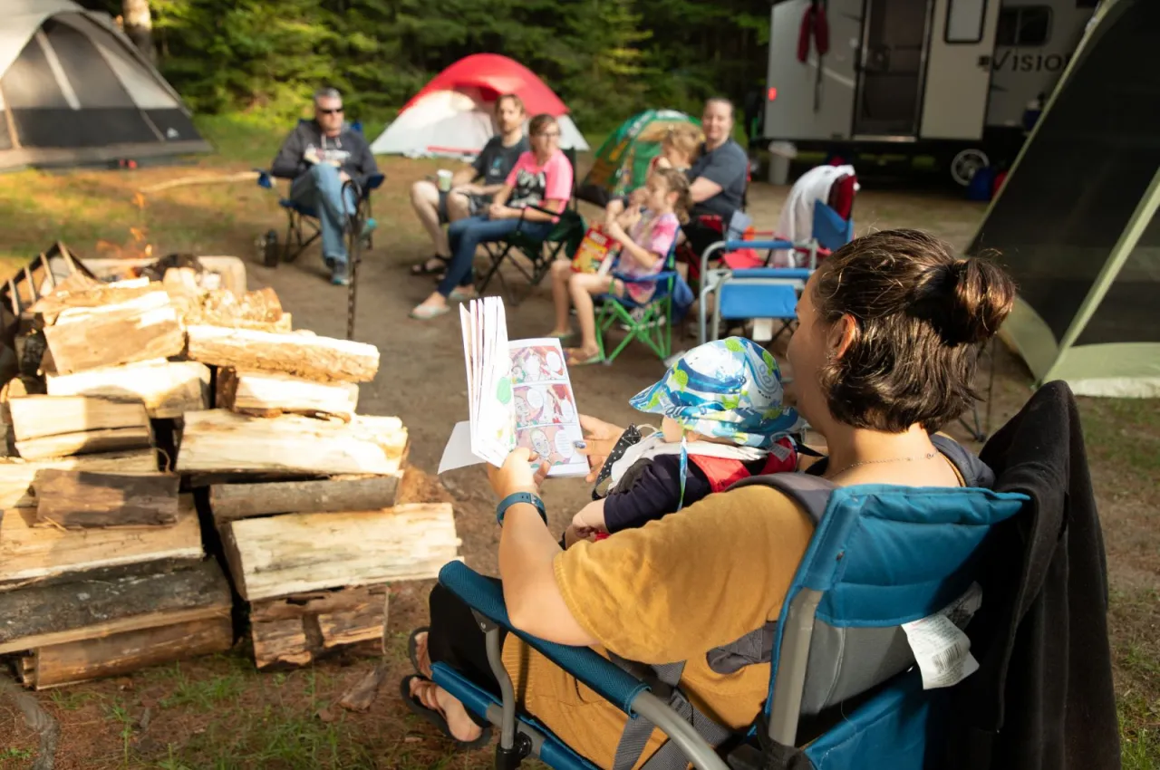 A group of people sit around a fire at a campground