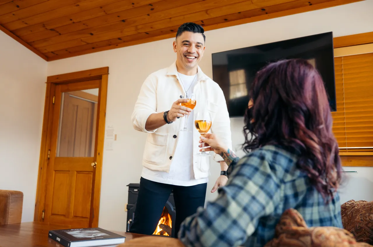 A man and woman cheers cocktails in an airbnb.