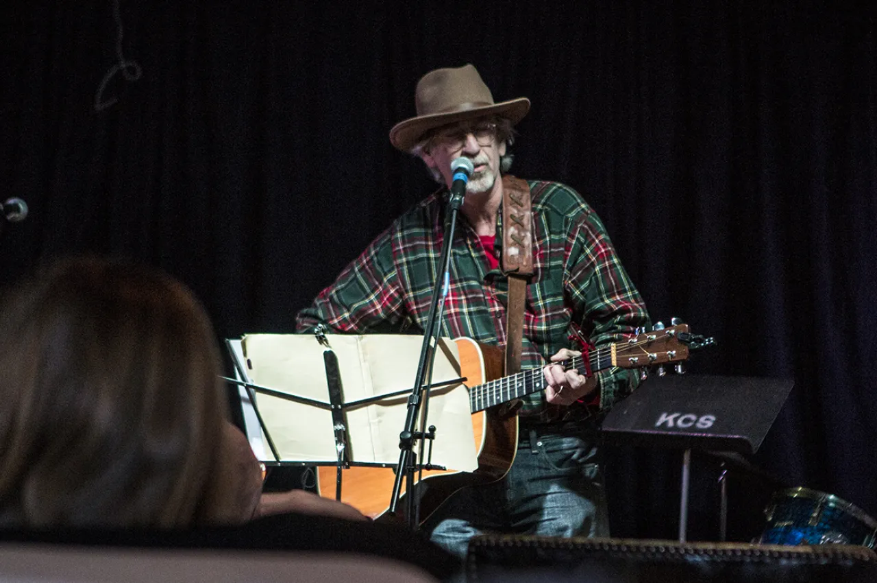 A man sings on a stage while playing his guitar.