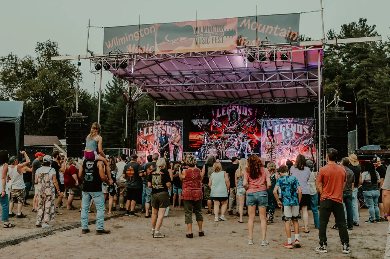 A crowd cheers for a rock band on a sunny day.