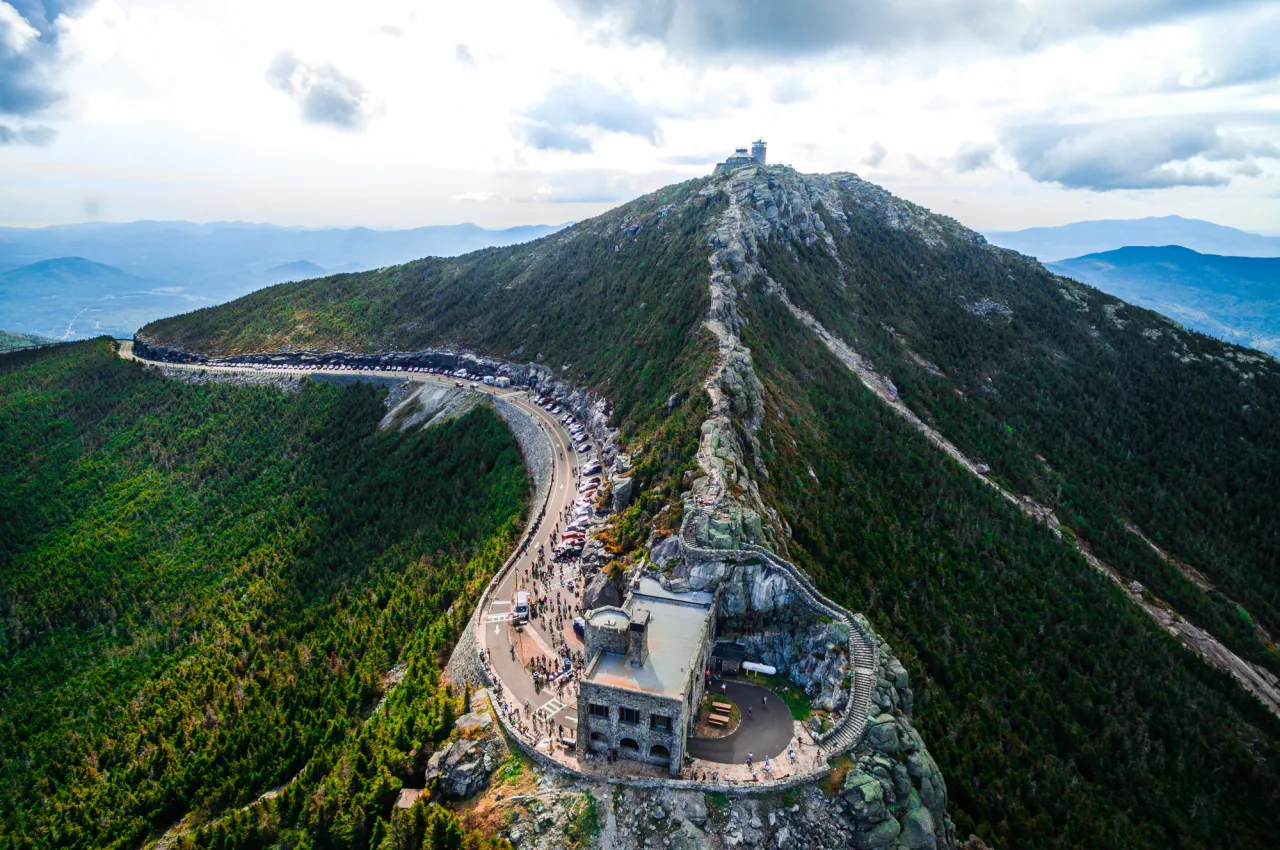 A highway wraps around a tall mountain in summer.