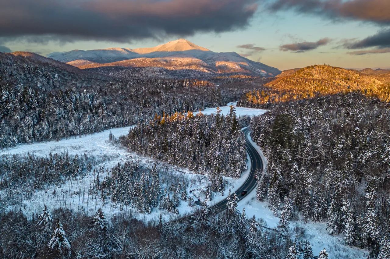 A road winds through a snowy scene in winter. 