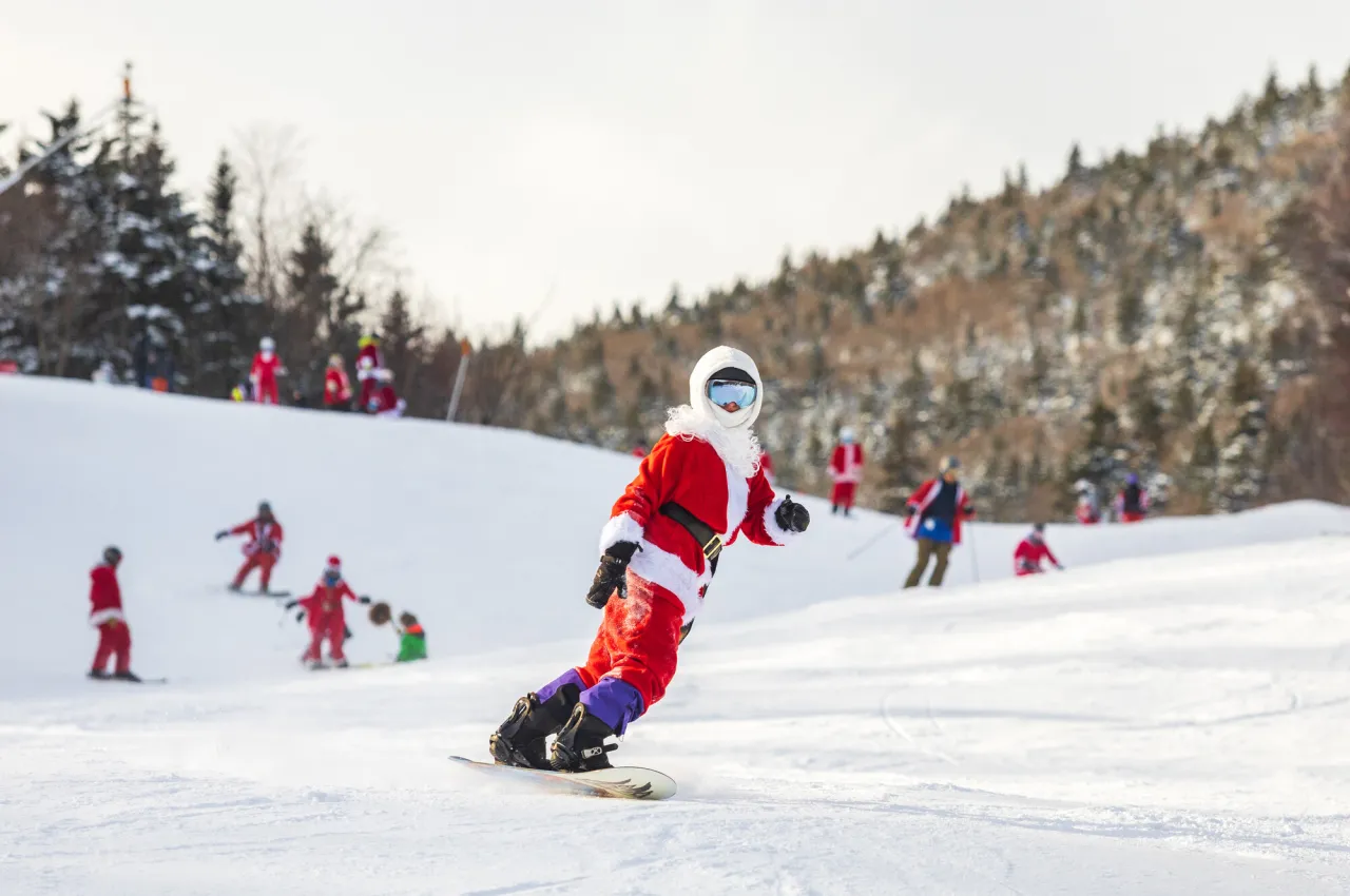 People dressed as Santa Clause ski down a mountain. 