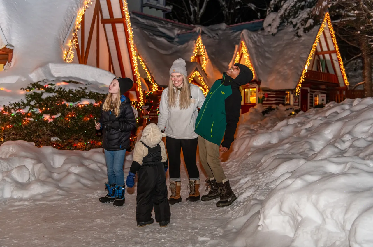 A family catches snowflakes on their tongues at a holiday village. 