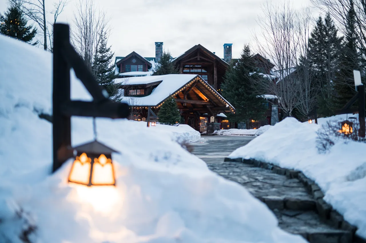 A grand rustic lodge tucked into a snowy scene. 