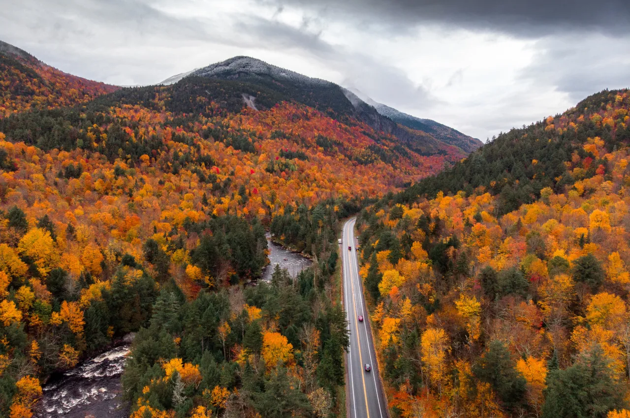 A road winding through a mountain range covered in fall foliage.