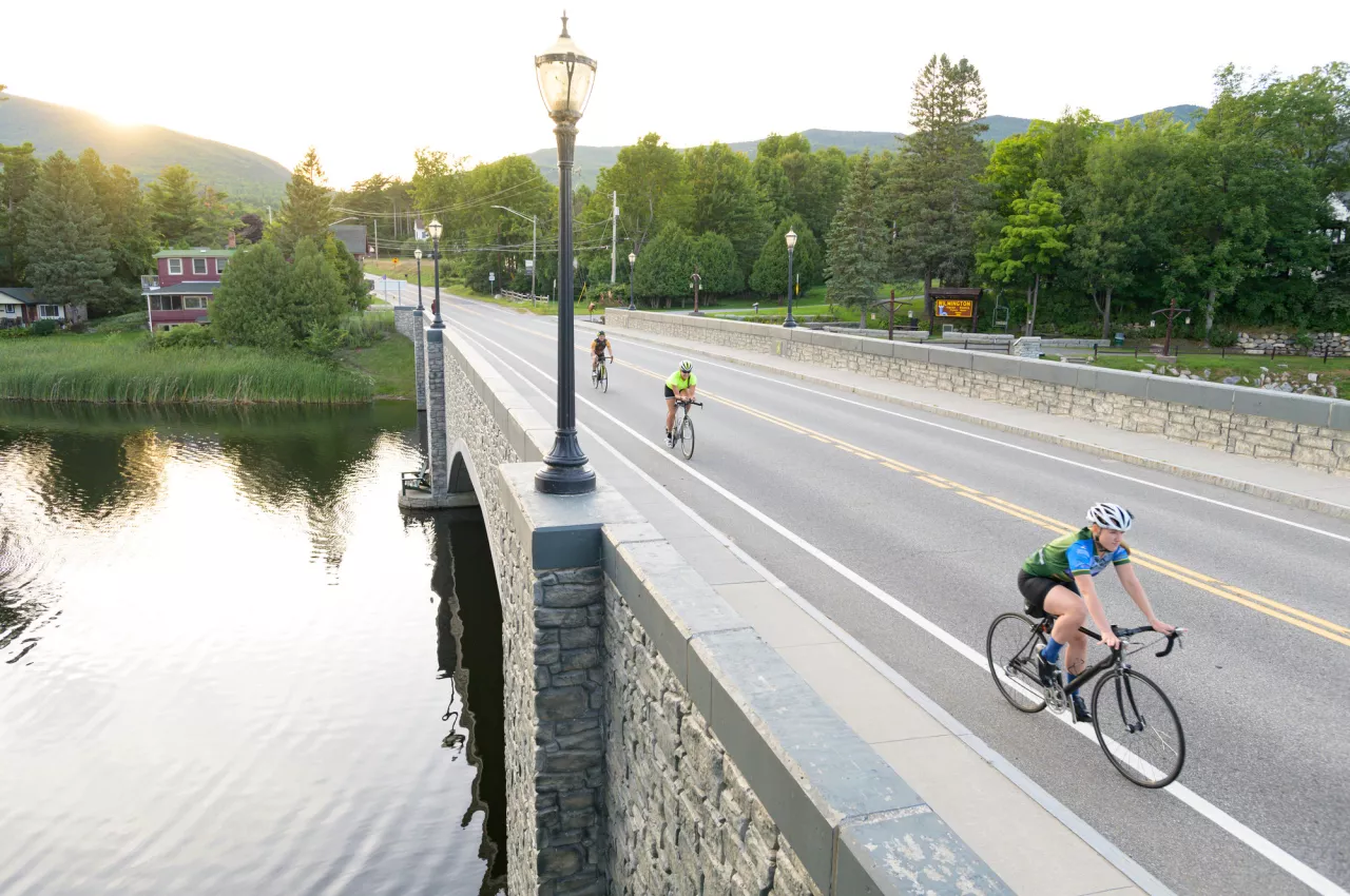 People road biking across a bridge