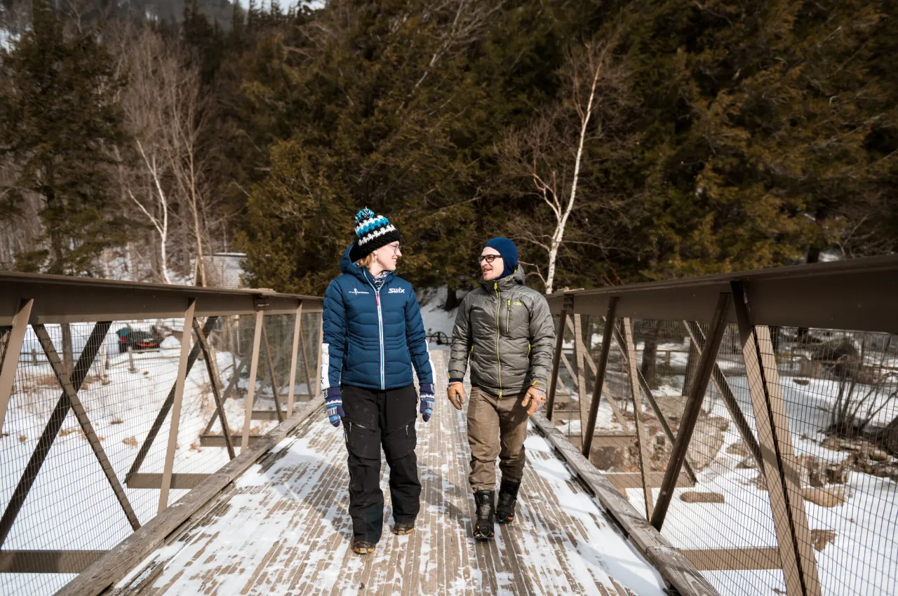 Two people walk across a snowy bridge in the winter