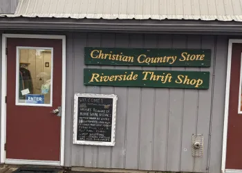 Grey exterior with red door of Riverside Thrift Store.