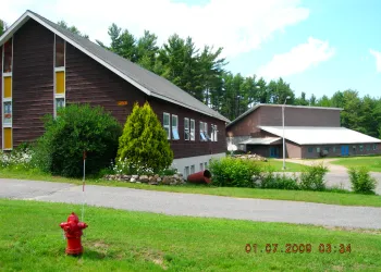 Exterior view of the lush grass and tall glass windows on the brown church.