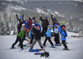 A group of skiers on the mountain waving at the camera