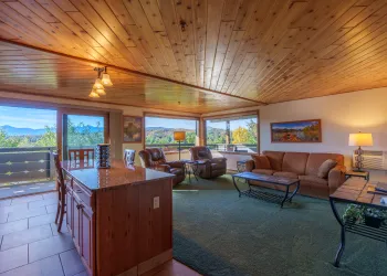 A large suite with dining space and comfortable couches and a view of the mountains from the balcony