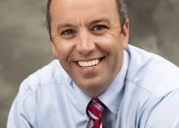 A smiling man in a red tie.