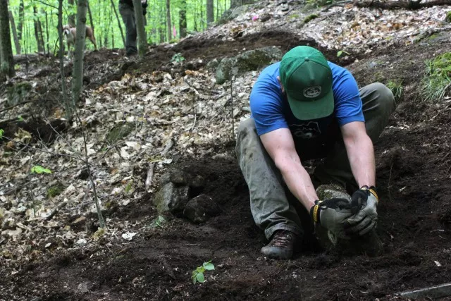 Josh Wilson rolls a rock while working on the Flume trail network.