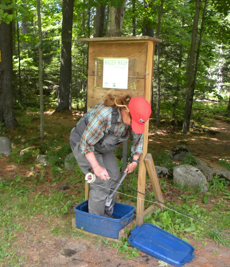 A woman using the wader wash station provided by the Ausable River Association.