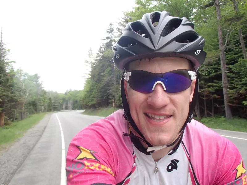 A cyclist in a pink jersey takes a selfie while biking along Route 9N