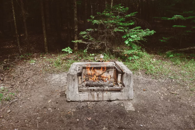 A fire pit at a campground with a small fire burning.