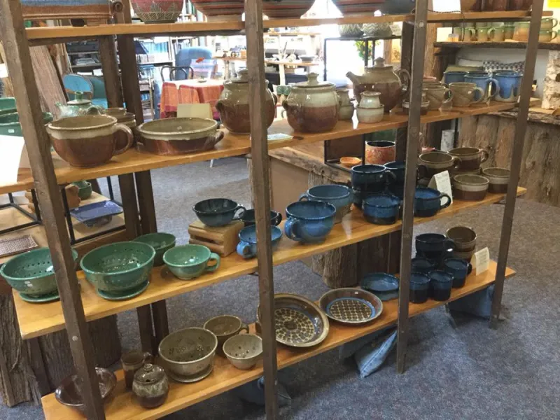 Wooden shelves filled with colorful pottery dishes, bowls, plates, and cups.