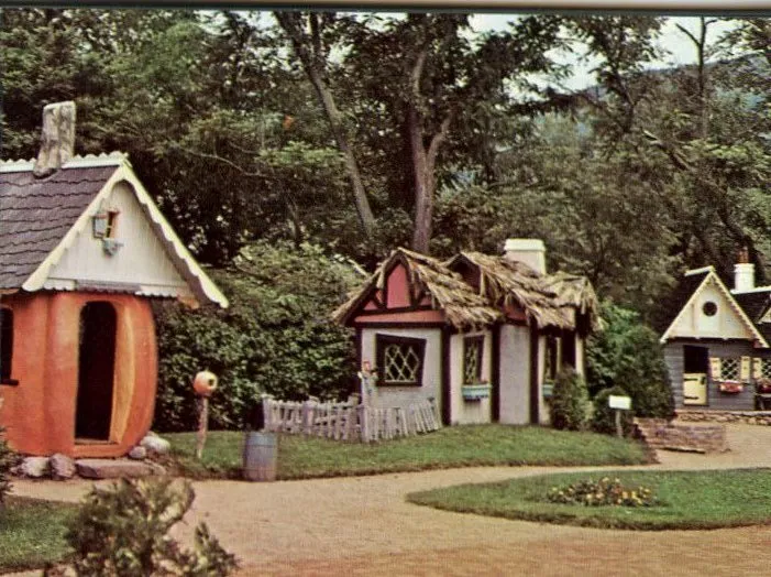 A vintage color image of child-sized storybook houses, including one that looks like a giant pumpkin.