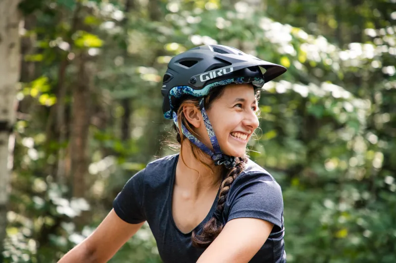 A woman wearing a mountain bike helmet smiles before going for a ride