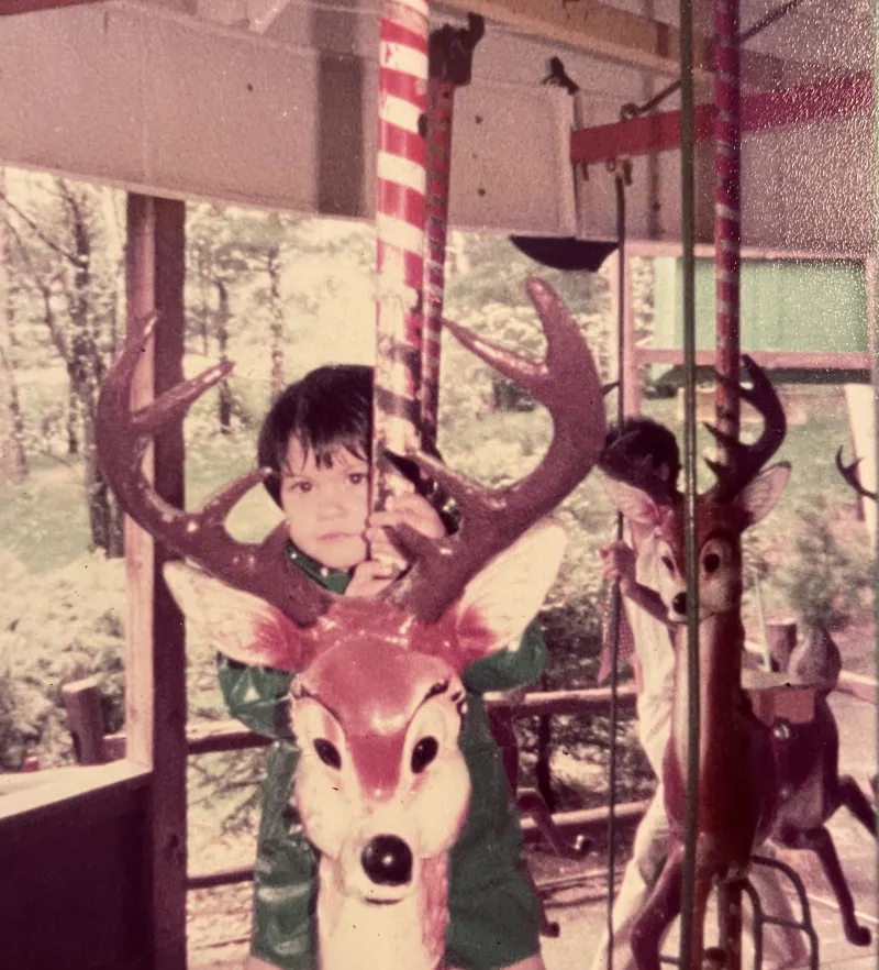A small child rides a reindeer on a Christmas-themed carousel.