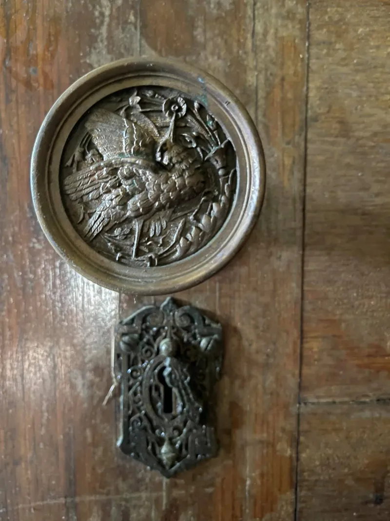 A close-up image of an intricate brass door knob featuring a bird.