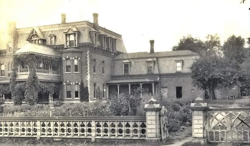 Vintage black and white photo of a mansion with gardens all around.