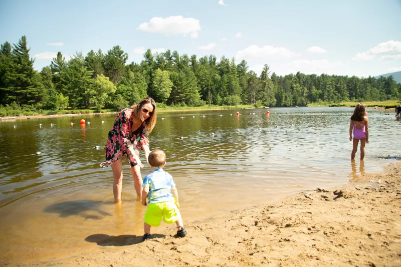 A mother and child play in the calm waters of a dammed section of the Ausable River.