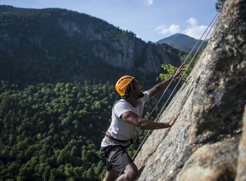 A man climbs a rock slab while rock climbing.